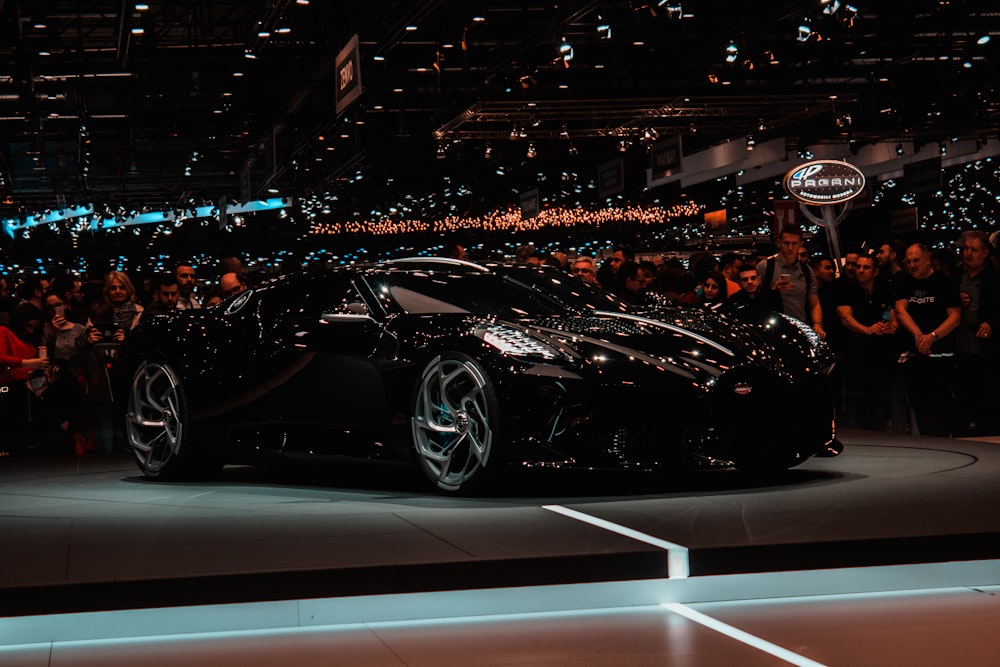 black sports car parked beside crowd