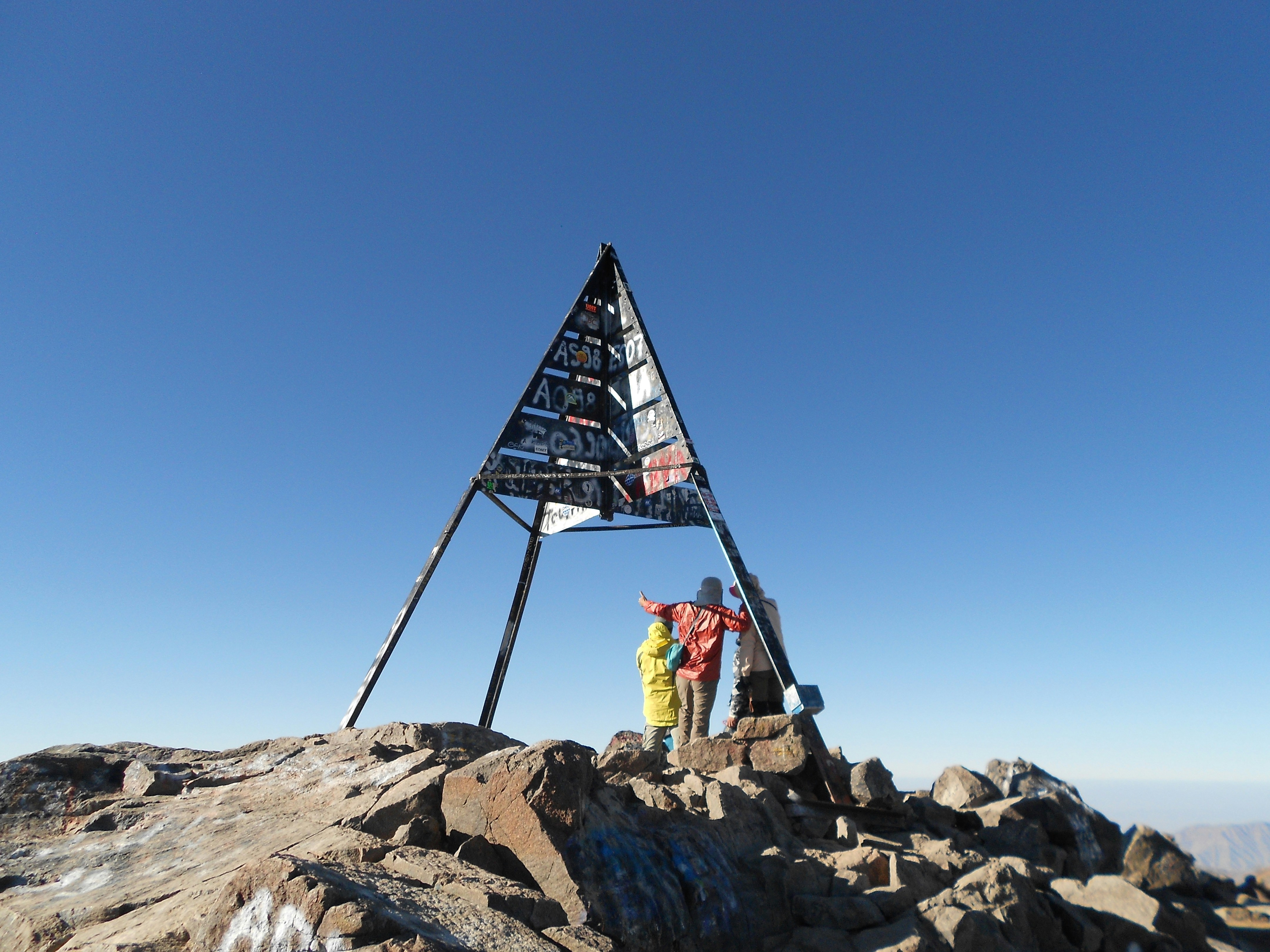 Happy group of travelers celebrating on mountain summit, bright golden hour lighting
