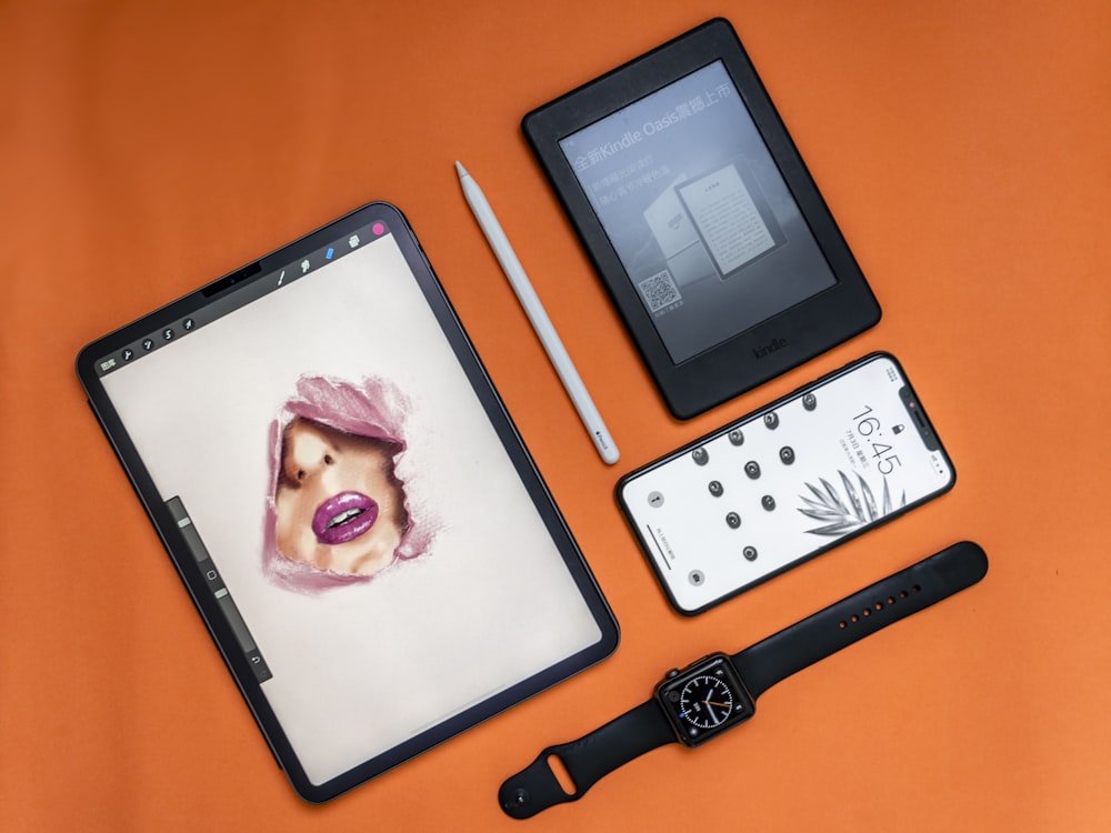 flat lay photography of two tablet computers, iPhone, and Apple watch