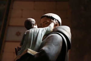 religious man carrying child statue