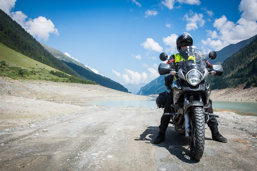 man riding motorcycle beside body of water