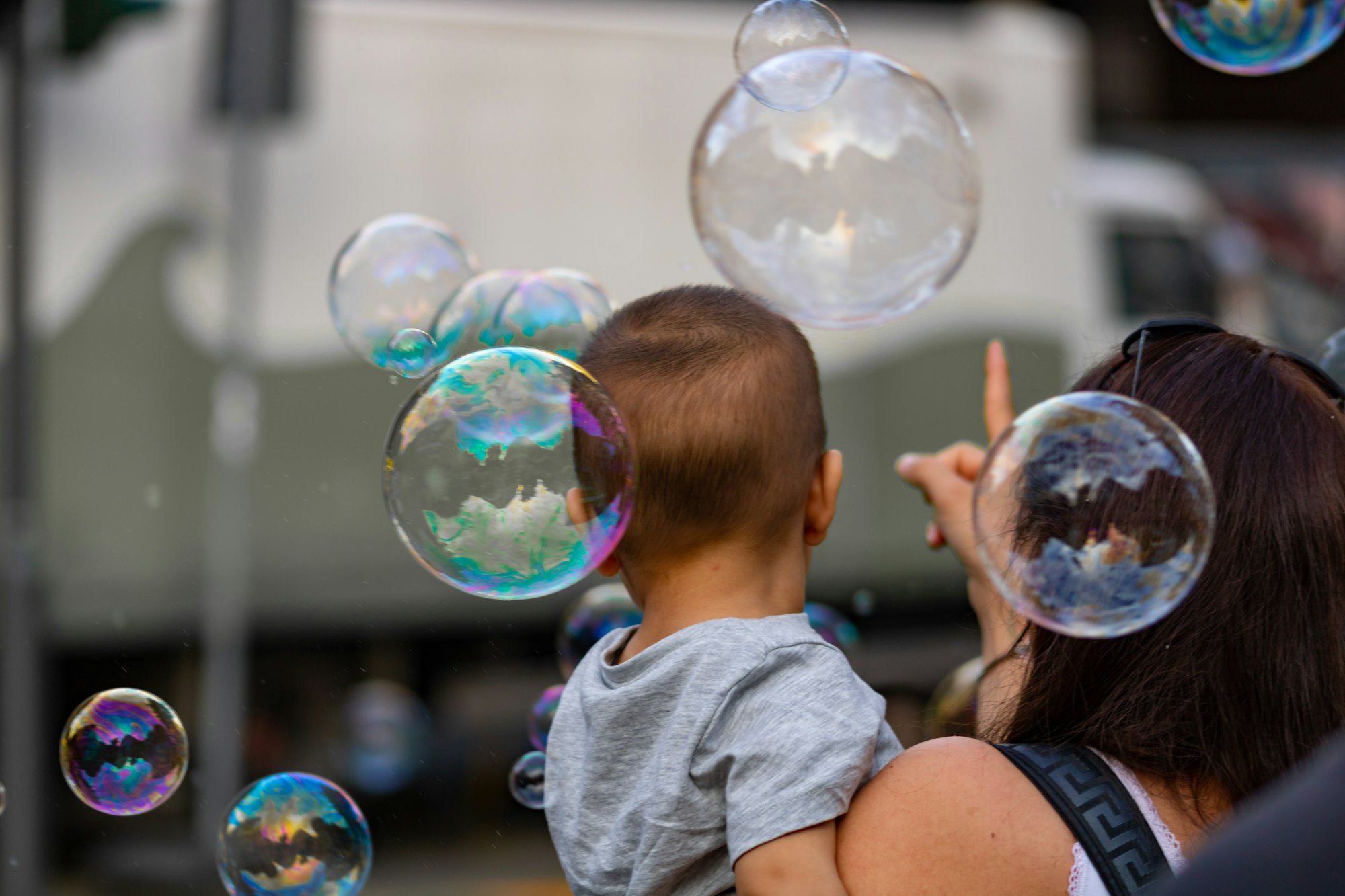 A mother her son looking at bubbles with rainbow colors.