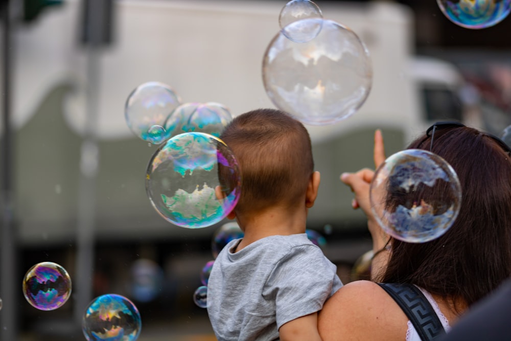 woman carrying baby near bubbles