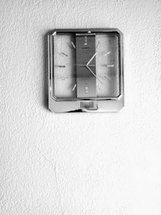 Close-up of a sleek wall clock crafted from a black vinyl record with visible grooves and a minimalist clock face.