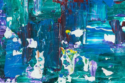 A vibrant abstract painting featuring bold brushstrokes and a mix of colors including green, blue, red, and white. The patterns are chaotic, with swirling and overlapping layers of paint creating a sense of depth and texture.