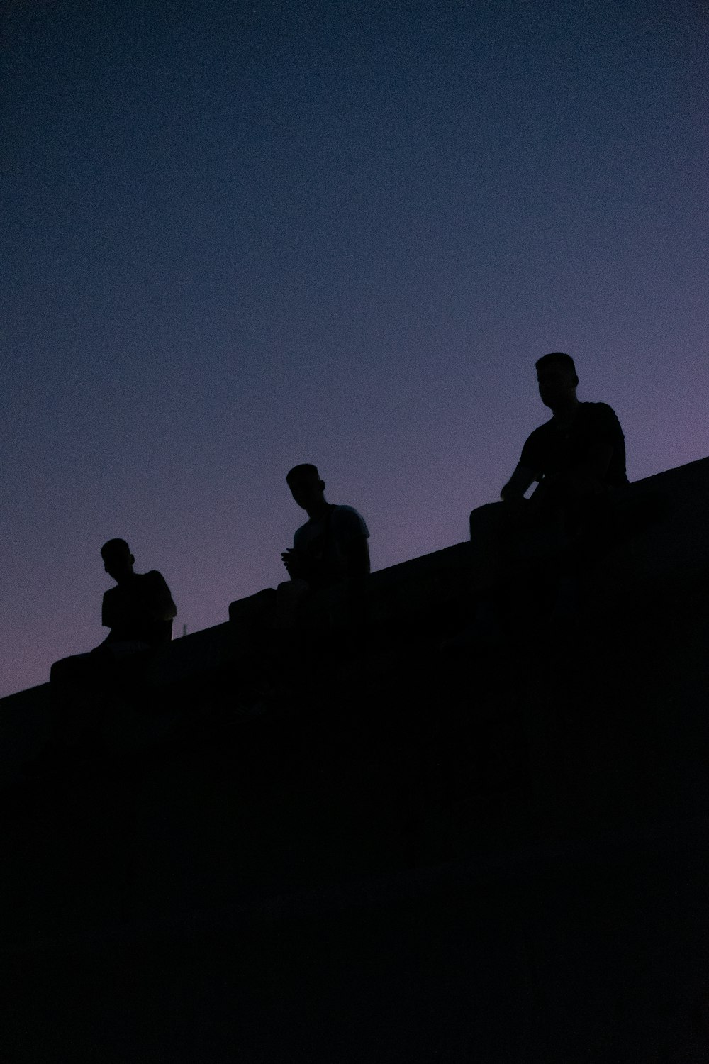 silhouette view of three men sitting on the roof