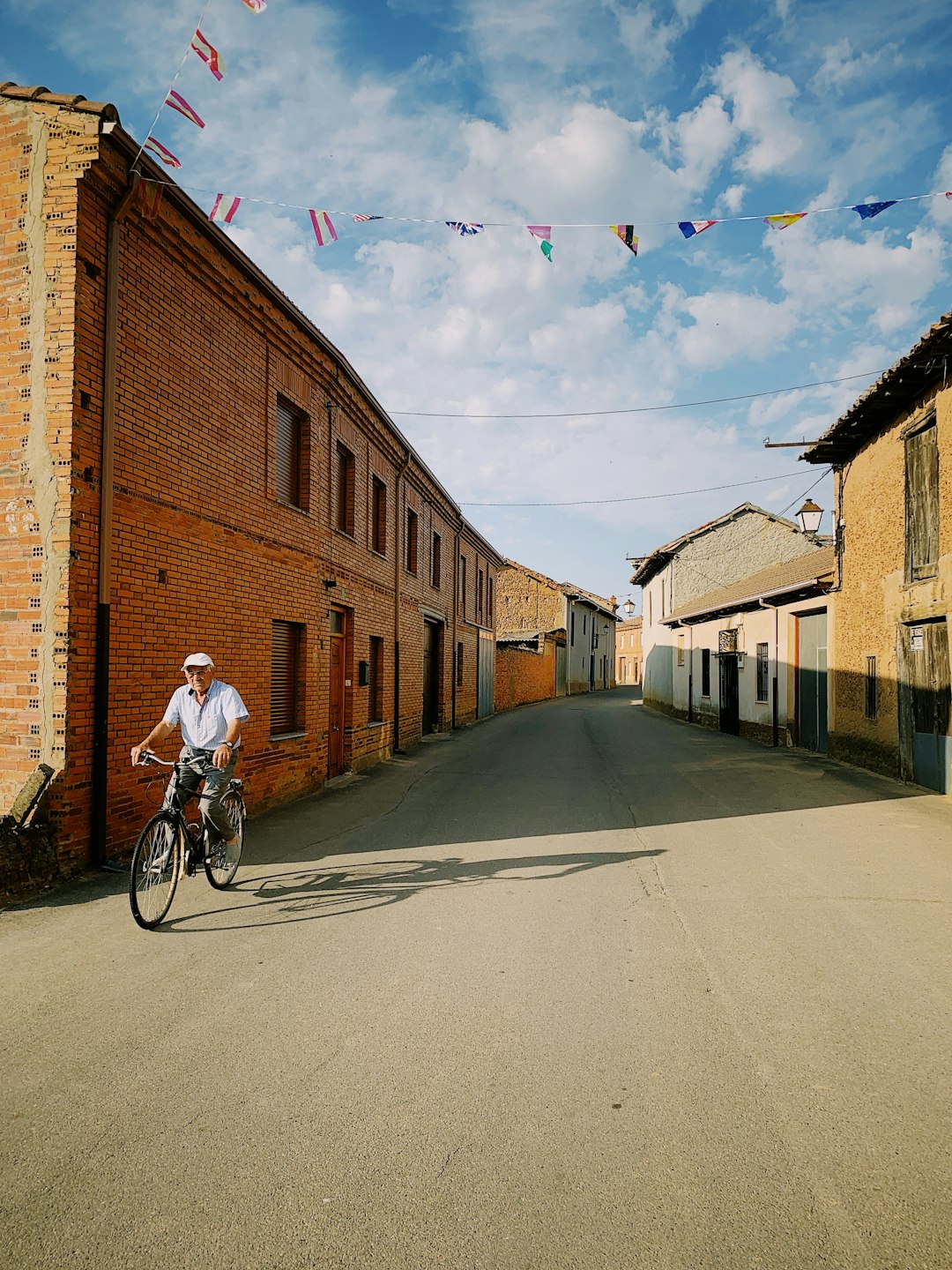 man riding bicycle beside brown building