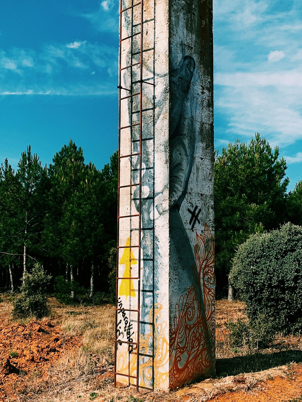 white and red concrete post surrounded with tall and green trees