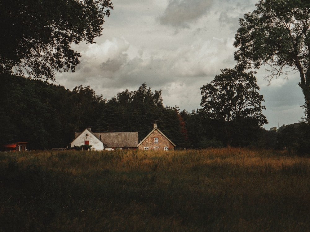 brown concrete house near green field surrounded with tall and green trees