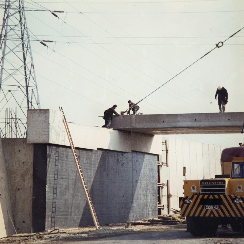 three people working bridge during daytime