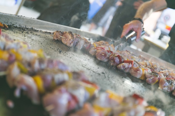 Close-up of a sizzling grill with skewers of meat and vegetables being cooked.