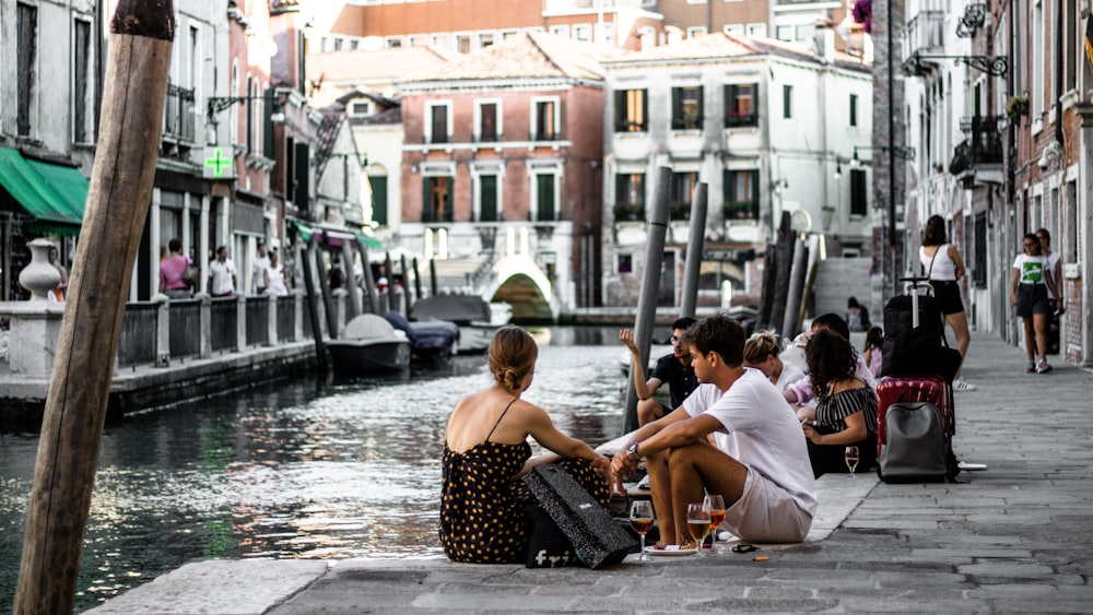 woman and man sitting on concrete ground with wine glasses