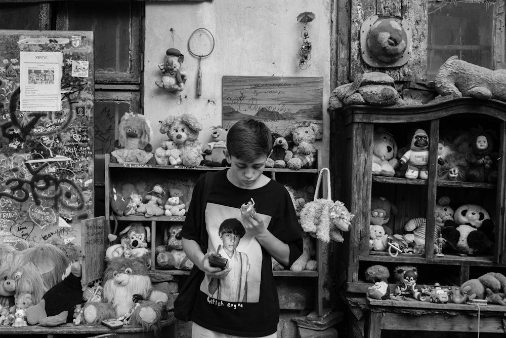 boy in t-shirt standing near plush toys on display