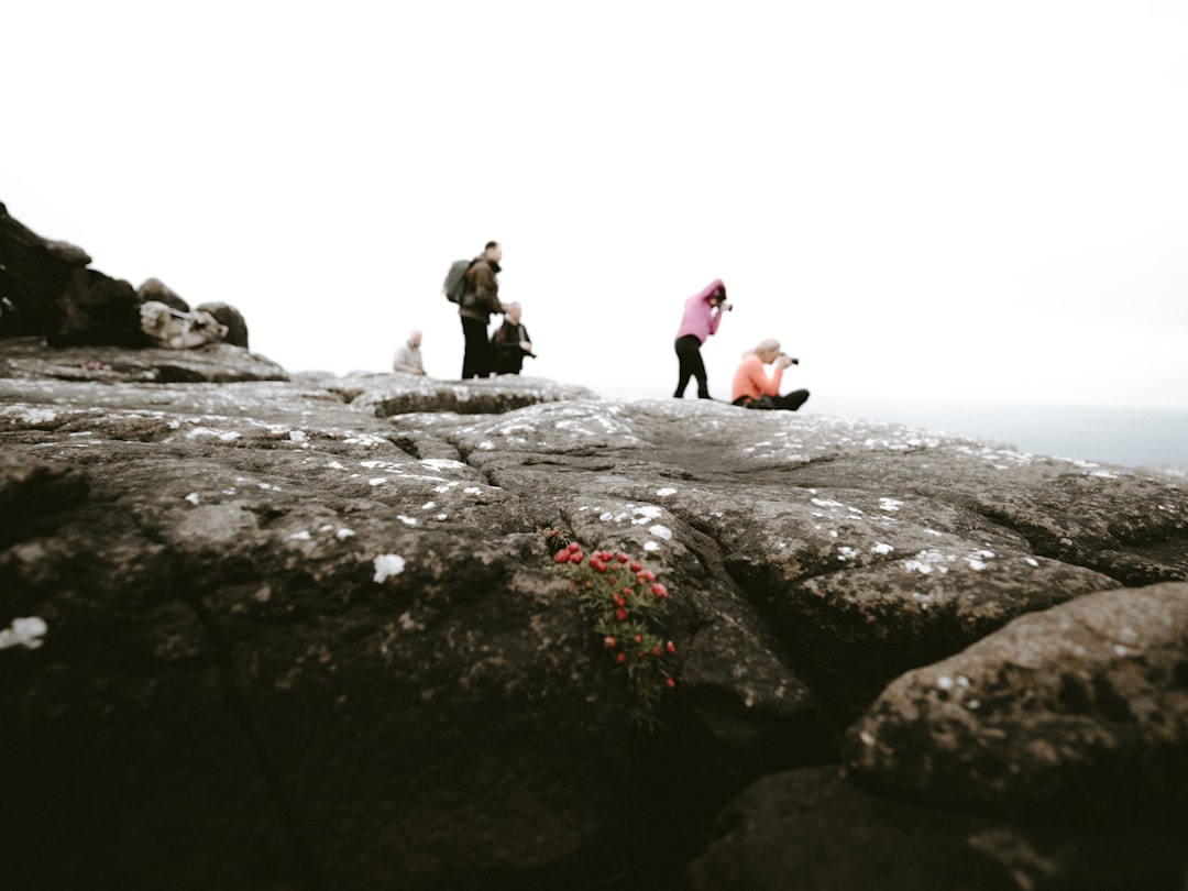 people sitting and others are standing on rocky hill