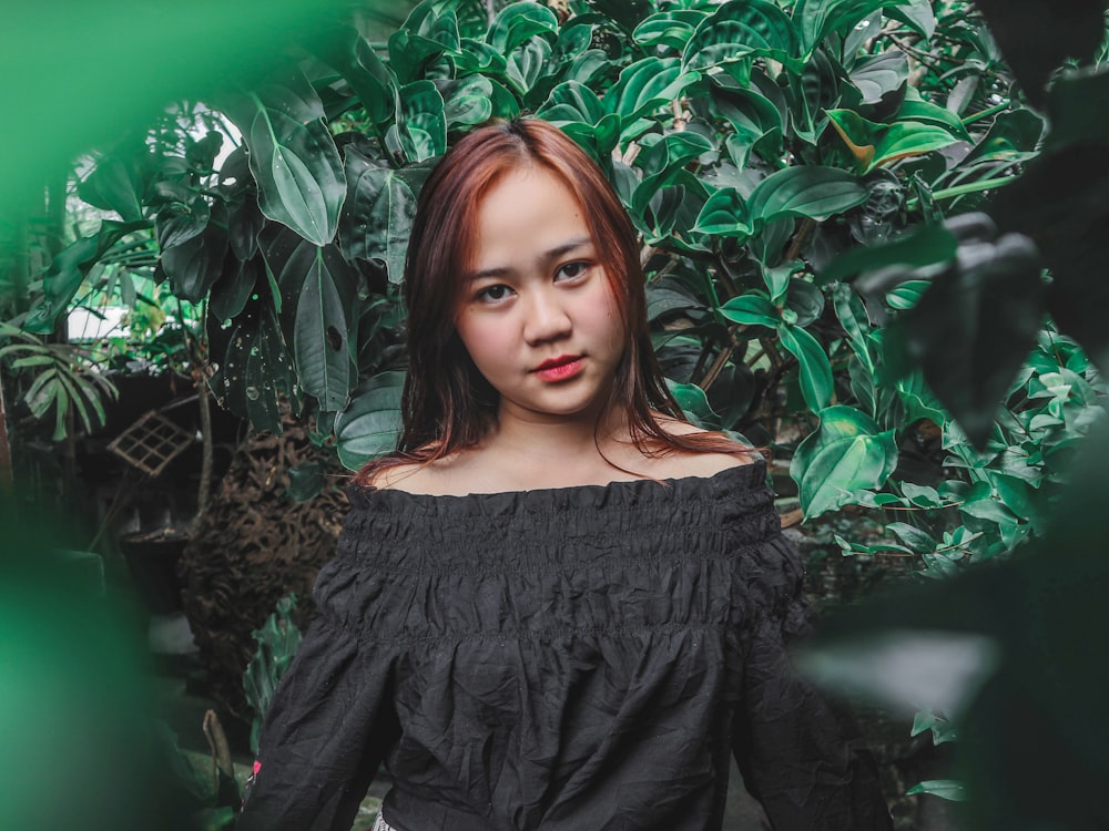 woman wearing black blouse standing near green leaf plants