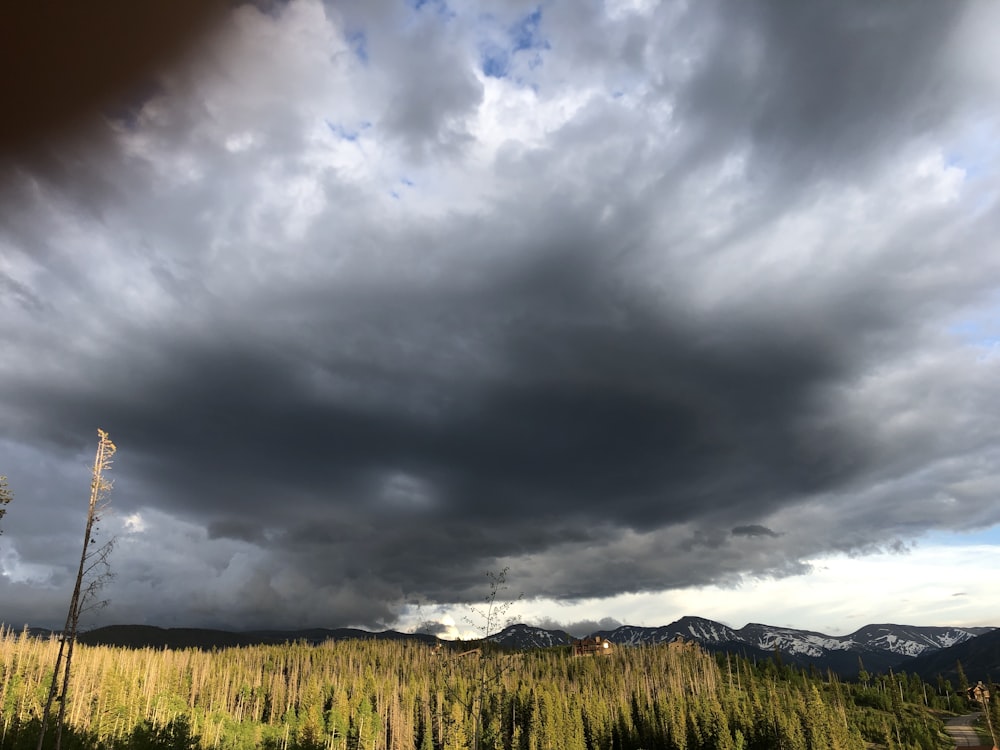 a cloudy sky over a field with mountains in the background