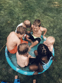 A group of children learning to swim safely in a calm community pool with an instructor guiding them.