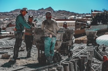 construction workers standing near wheelbarrows near mountain