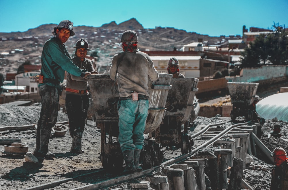 Bauarbeiter stehen in der Nähe von Schubkarren in der Nähe des Berges