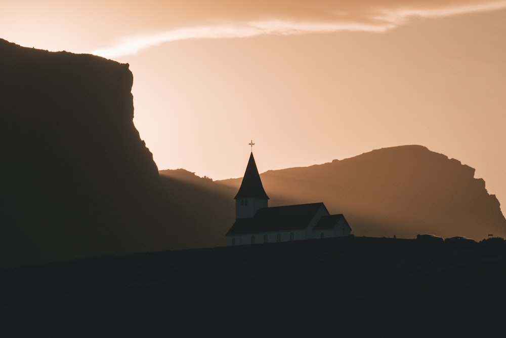 white and black church at mountain top under sunset sky