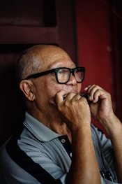 man in grey and black polo shirt using harmonica