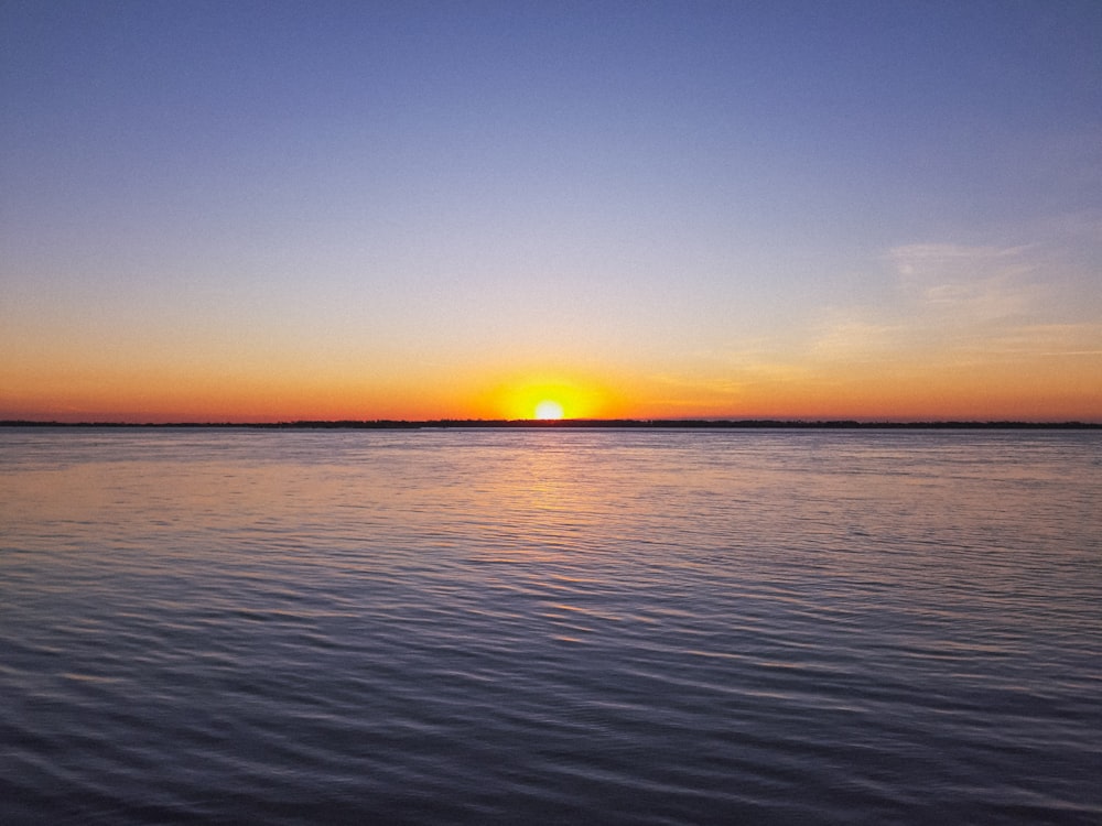 blue calm sea during sunrise