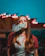 A happy young woman vaping with neon-colored lights in the background.