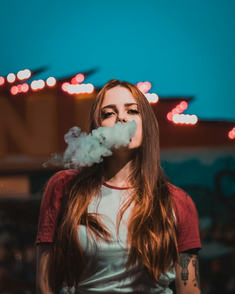 woman in white and red raglan t-shirt smoking