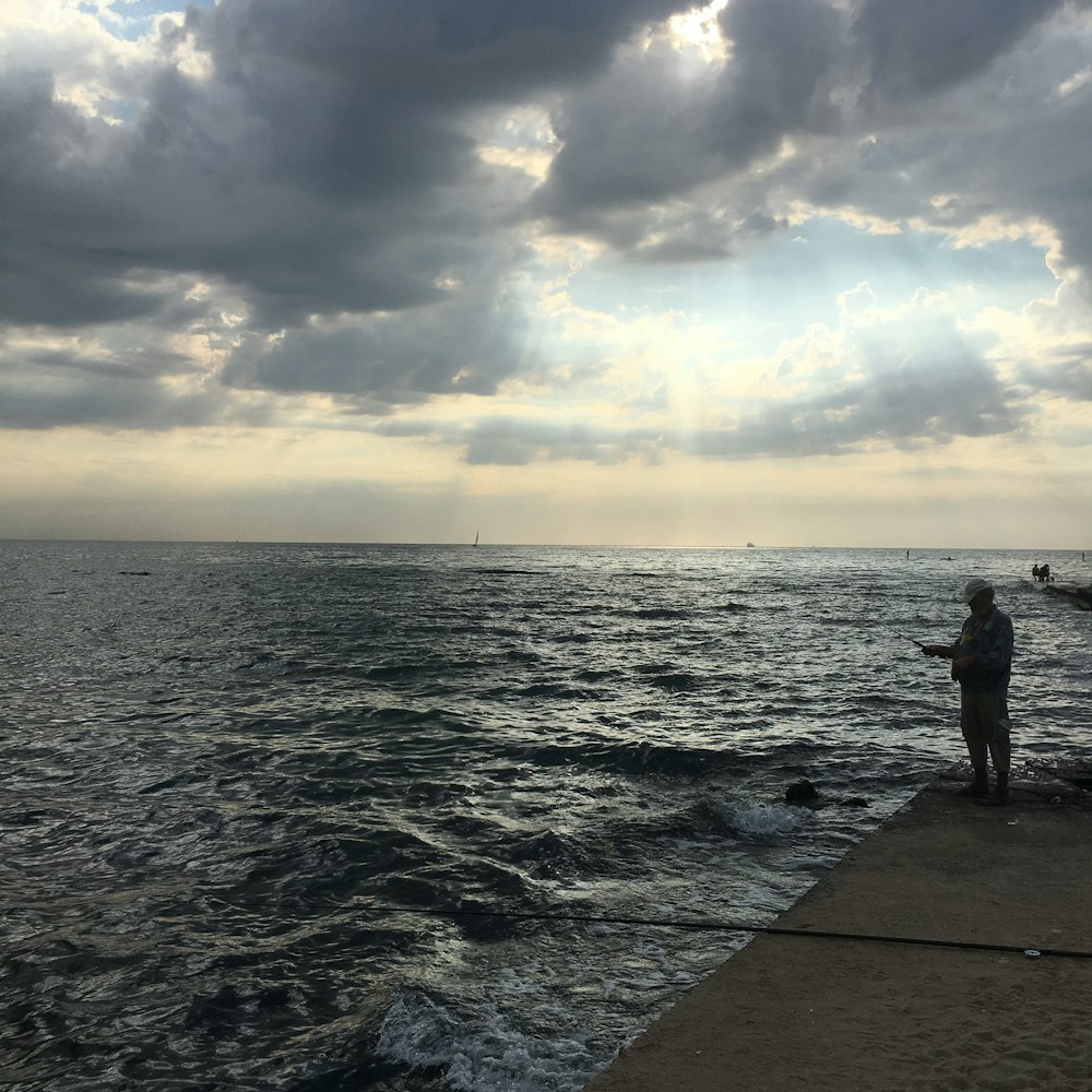 man standing in pier near water