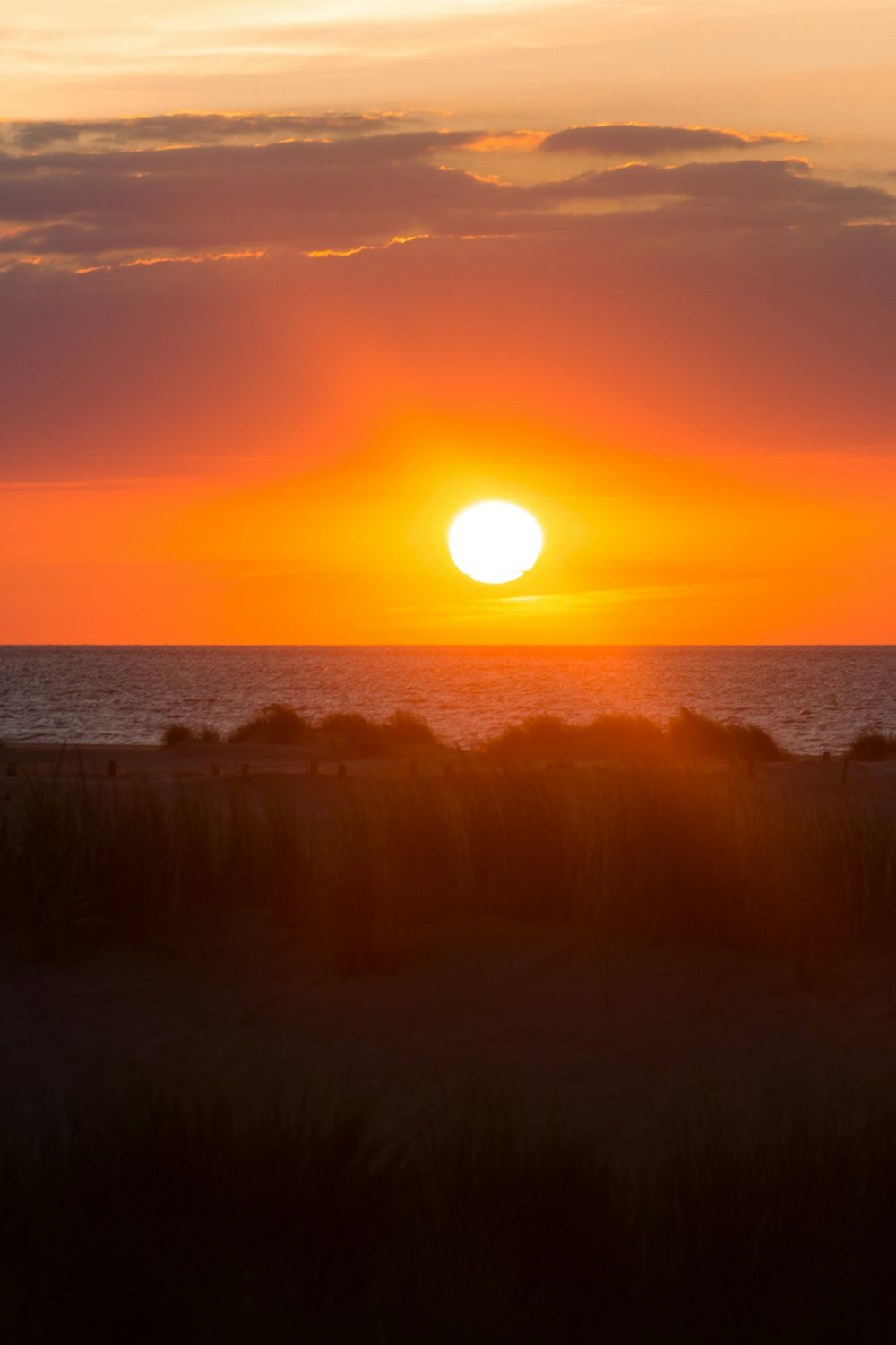 the sun is setting over the ocean on a cloudy day