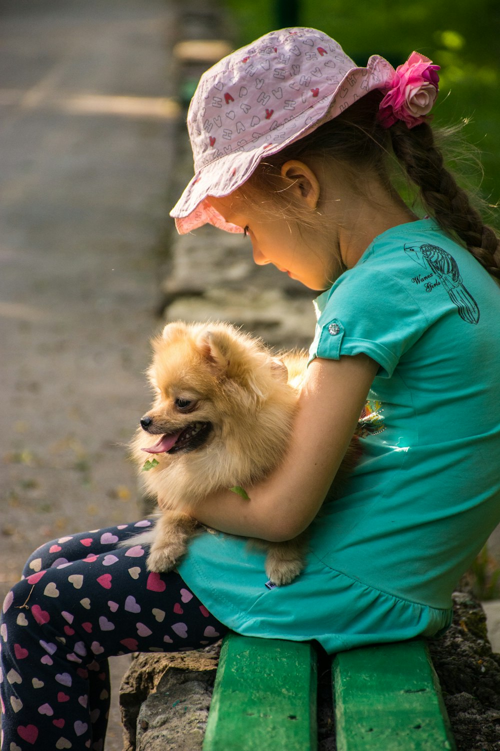girl sitting and carrying brown Pomeranian puppy