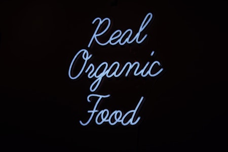 Neon sign displaying the words 'Real Organic Food' in a flowing script against a dark background.