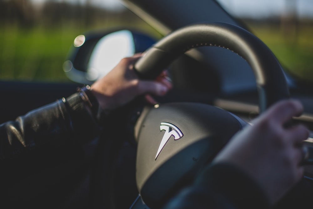 person holding black Tesla steering wheel