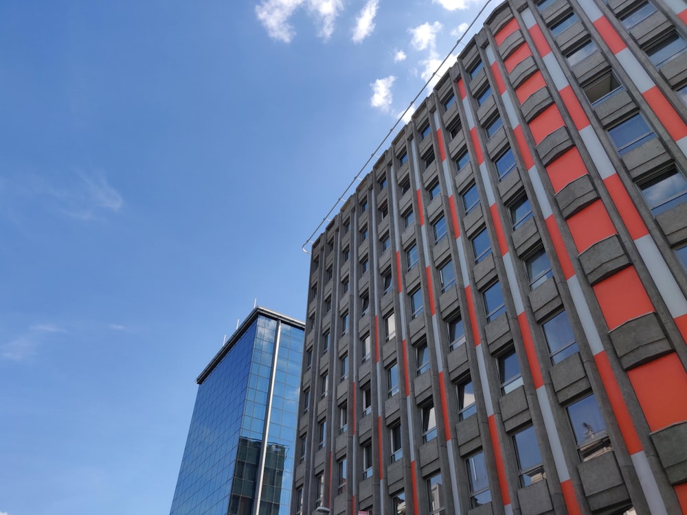 Des gratte-ciel gris et orange sous un ciel bleu et blanc