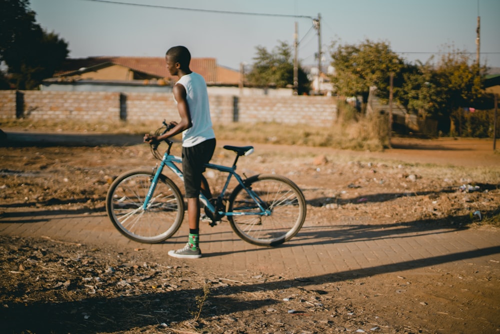 man standing beside rigid bicycle