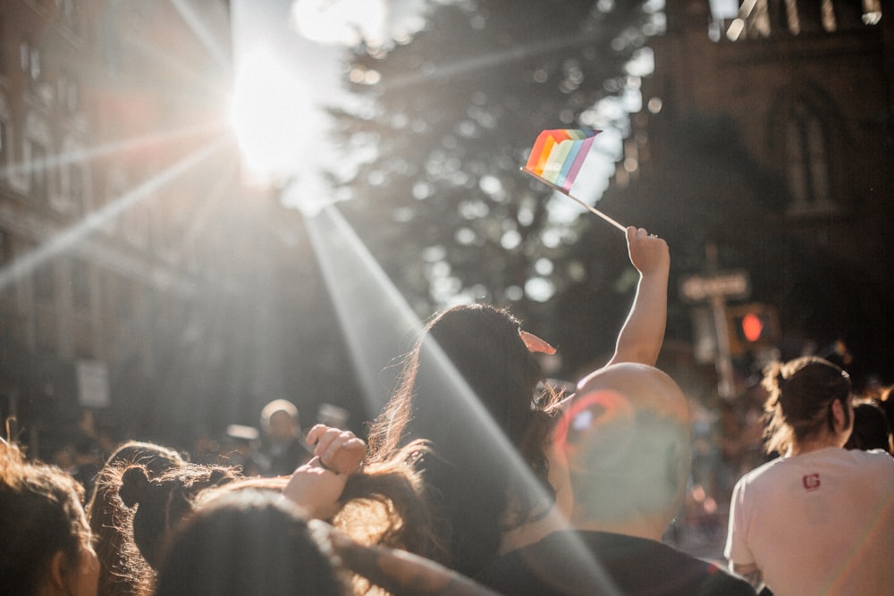 woman raising rainbow flag in crowd