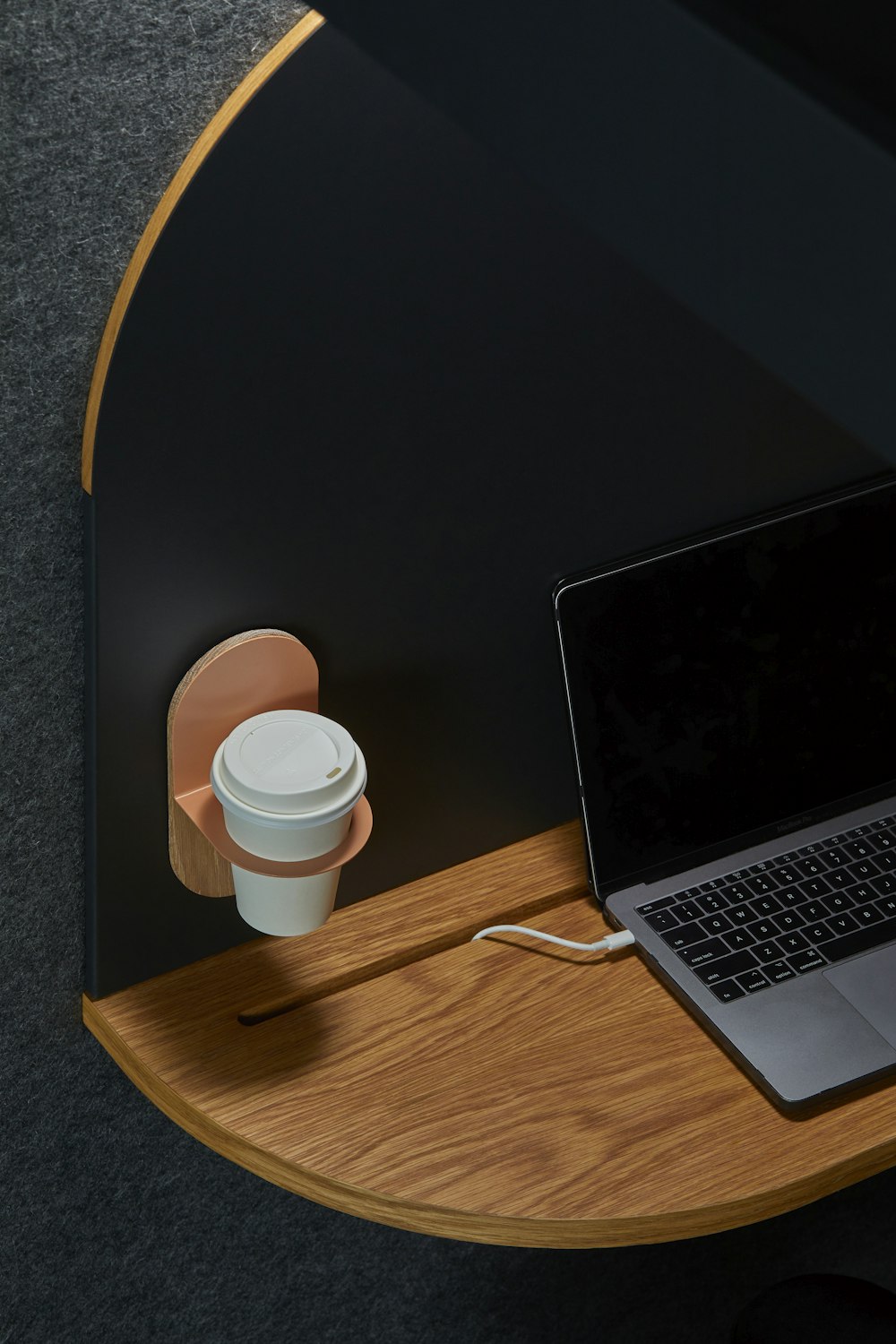 black laptop computer on brown table beside hanged white cup