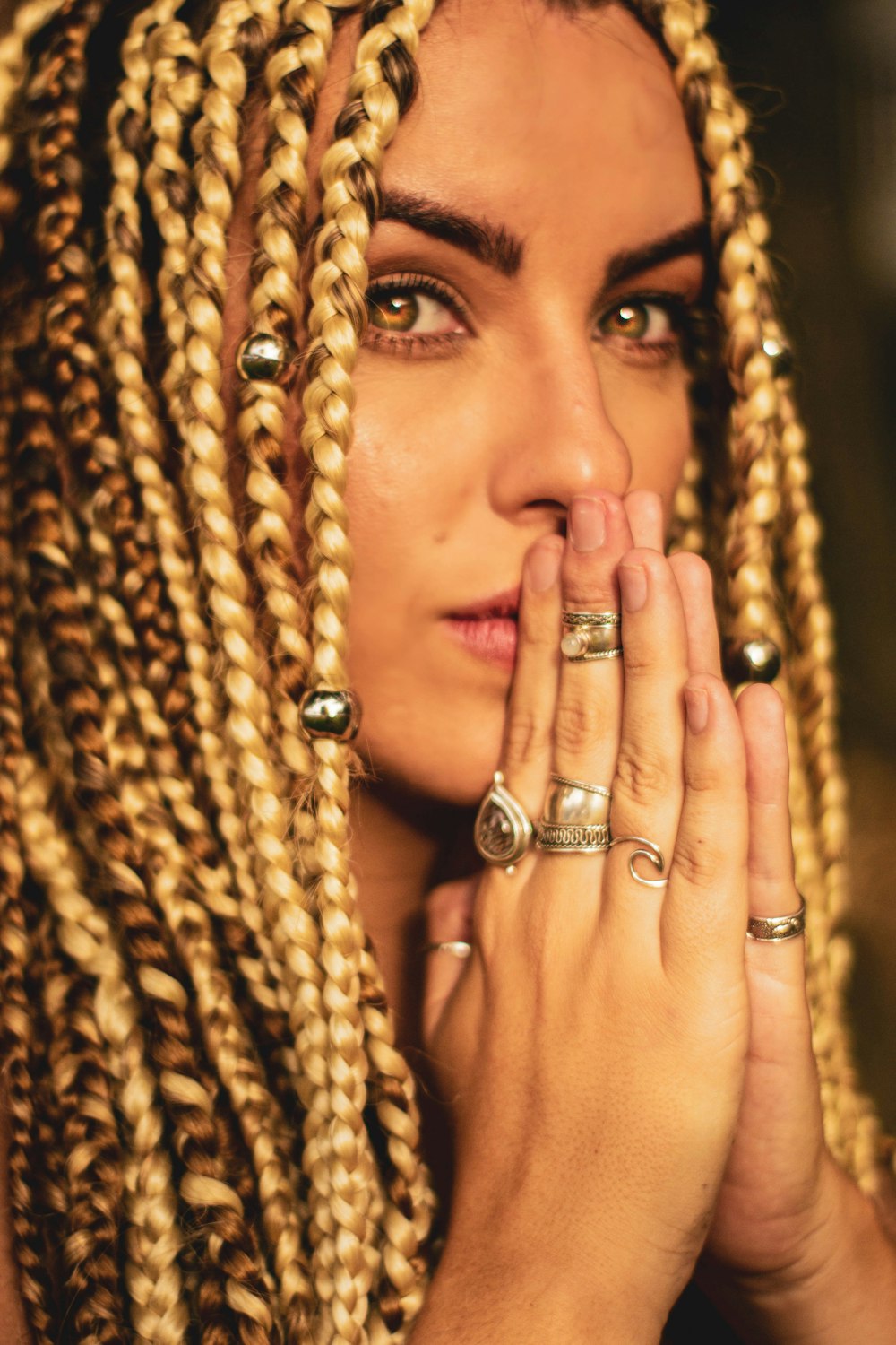 woman with braided hair putting hands near her mouth