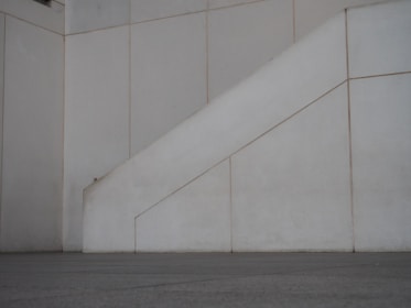 Minimalist urban scene with clean lines and shadows playing across a white concrete wall.
