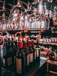 Sophisticated arrangement of wine, whisky, and tequila bottles illuminated by warm ambient lighting in an elegant setting