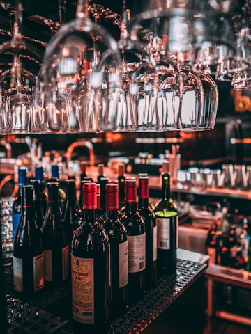 Sophisticated arrangement of wine, whisky, and tequila bottles illuminated by warm ambient lighting in an elegant setting