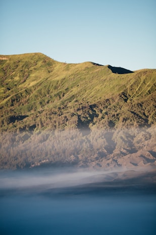 A serene sunrise over a misty mountain range with lush greenery.