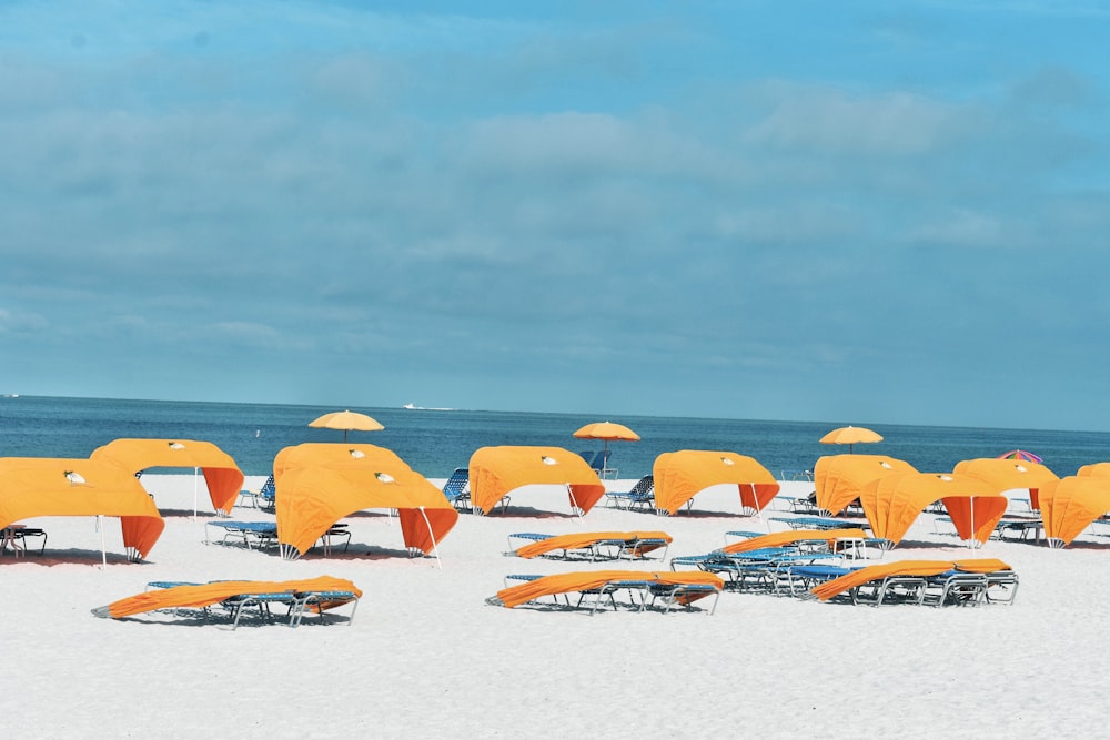 chairs and tens on white sand beach during daytime