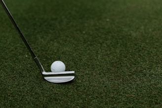 A close-up of golf clubs and balls arranged neatly on a green grass surface.