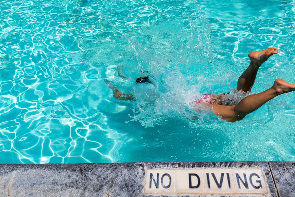 pessoa mergulhando na piscina durante o dia