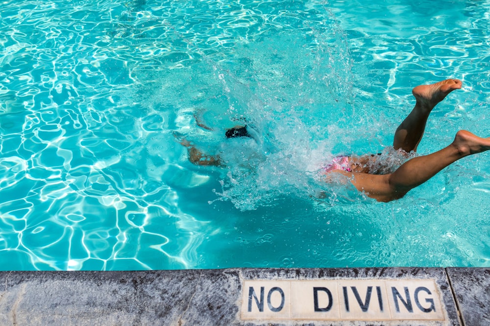 person diving on pool during daytime