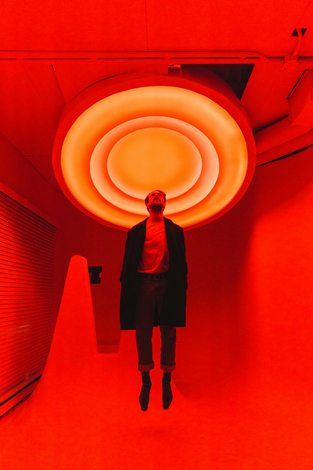 Mann steht unter großem rotem Licht im Raum