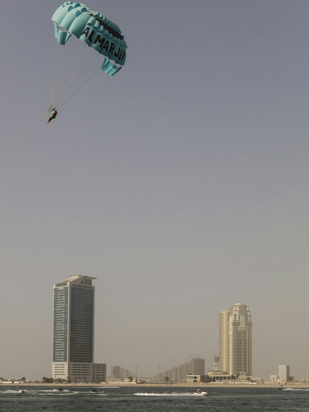 person in parachute above the water