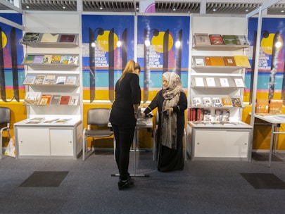 Authors engaging with visitors at a book signing booth filled with colorful books.