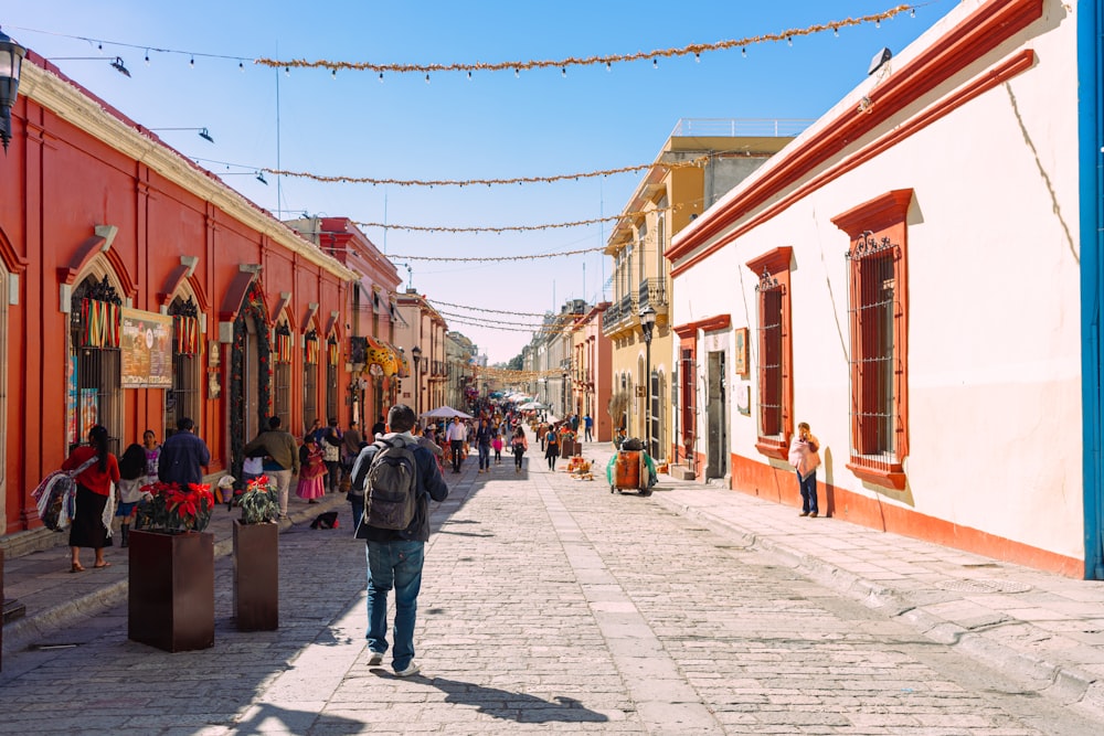 Un hombre caminando por una calle junto a edificios altos